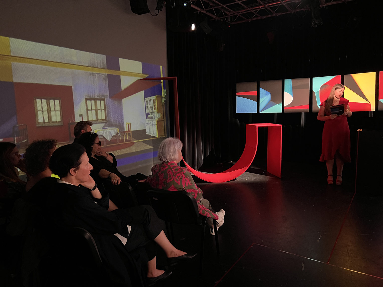 Kobieta stojąca przed grupą ludzi siedzących na widowni.