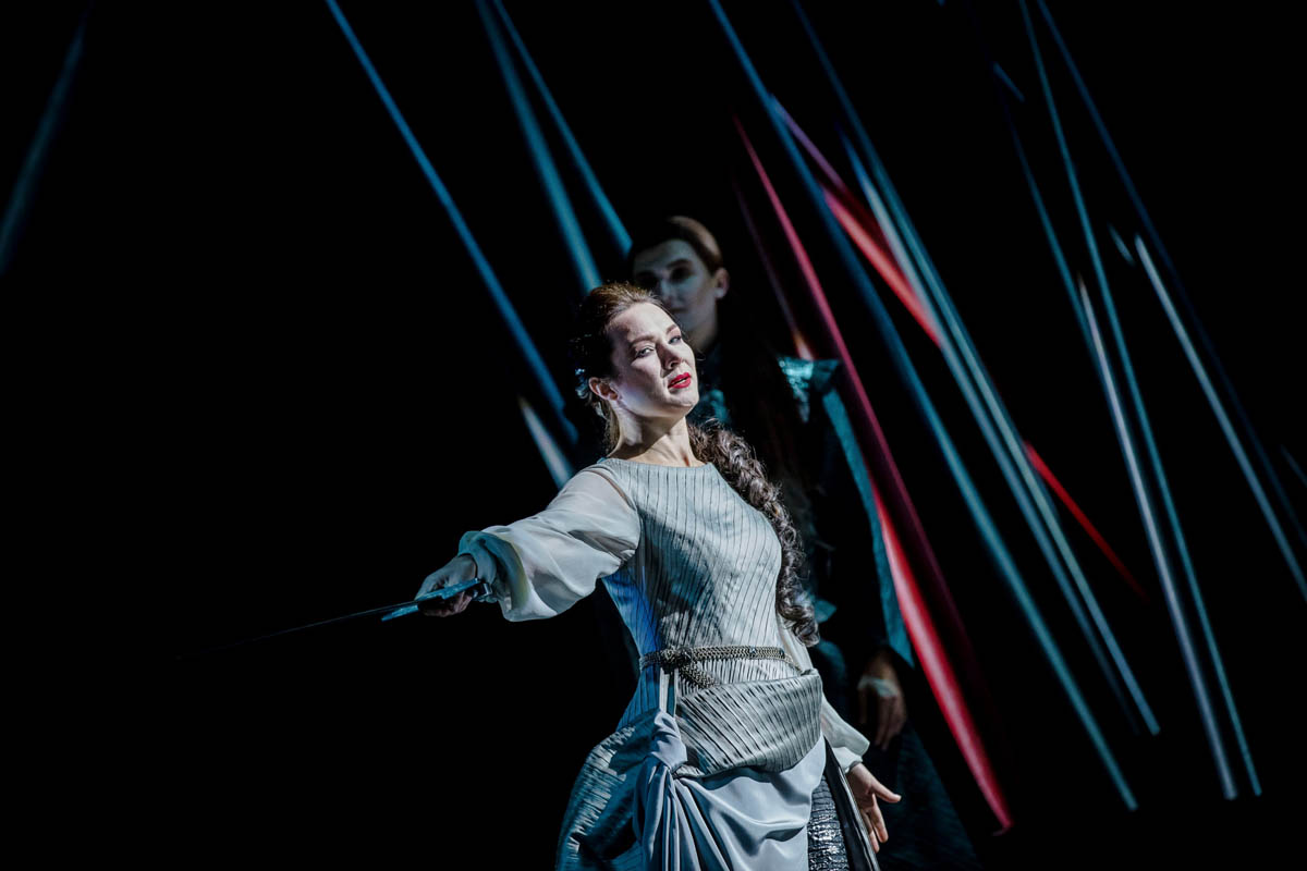 Klęcząca kobieta z zbroi rycerskiej z wyciągniętymi ramionami.