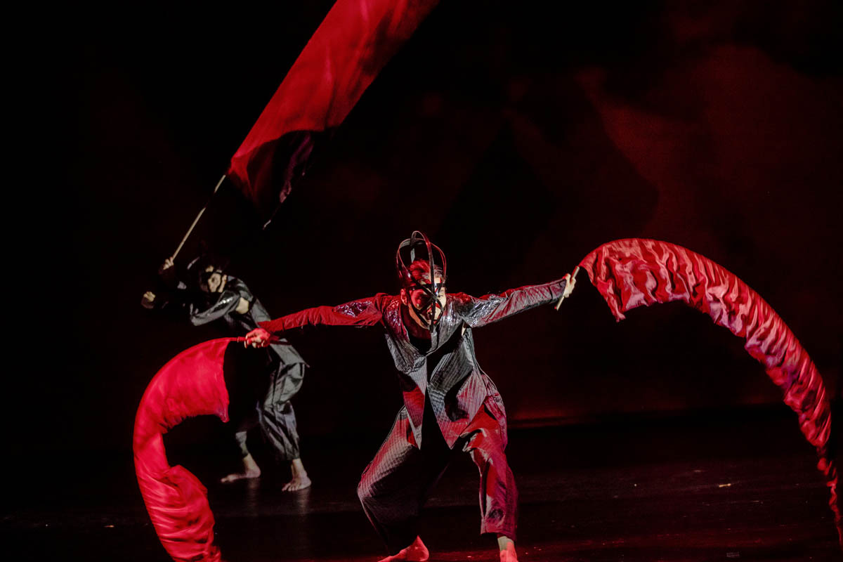 12. Dwaj mężczyźni w obcisłych strojach poruszają się gwałtownie. W dłoniach trzymają cienkie kije z przytroczonymi do nich pasami cienkiej tkaniny imitującej płomienie ognia.