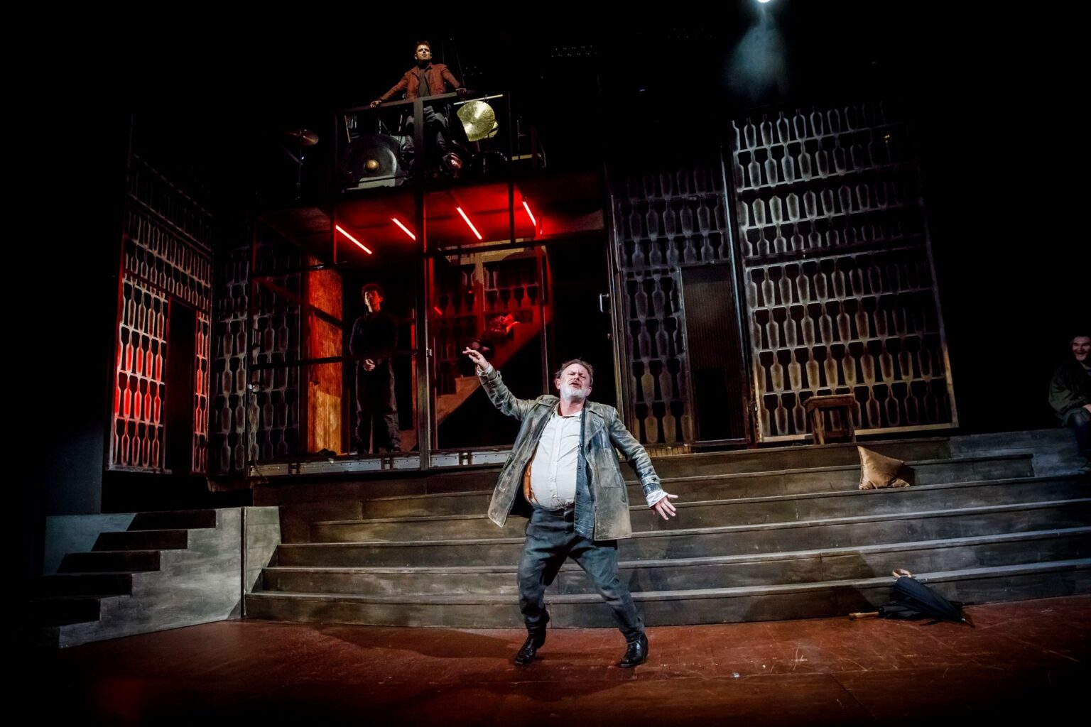 Trzech aktorów stojących na tle scenografii