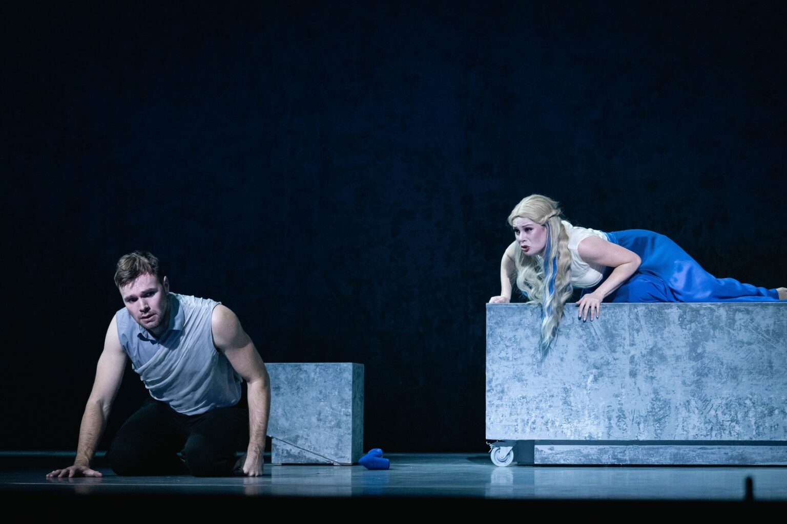 Mężczyzna siedzący na ziemi, kobieta leży na postumencie