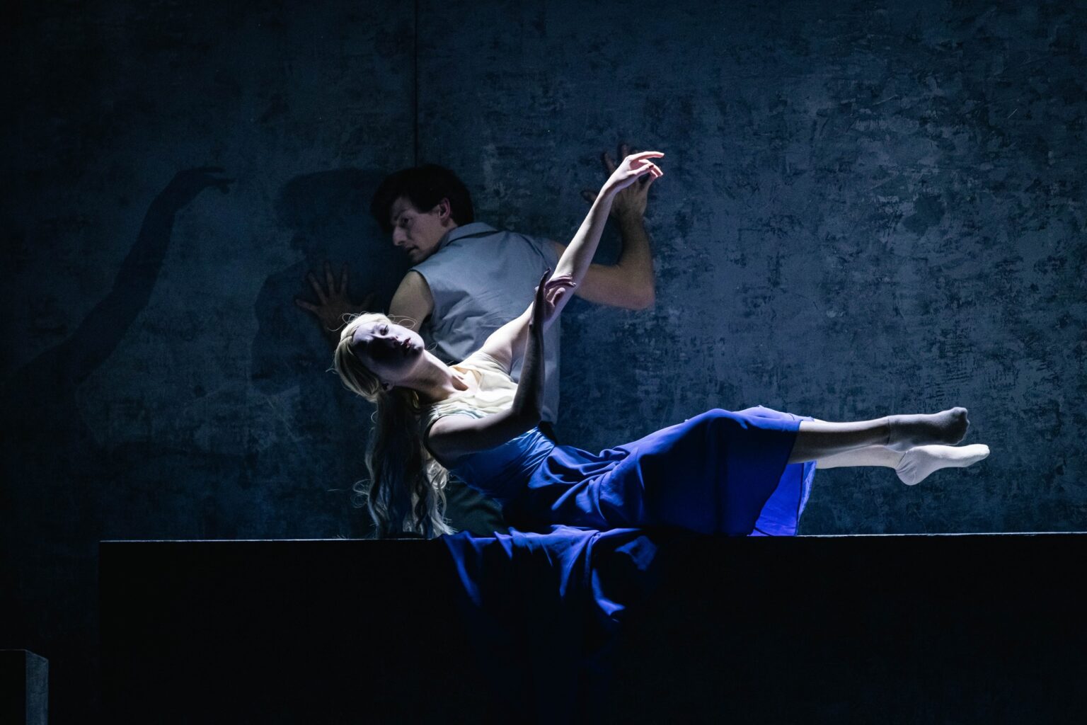 Leżąca kobieta w długich, blond włosach w biało-niebieskiej sukience