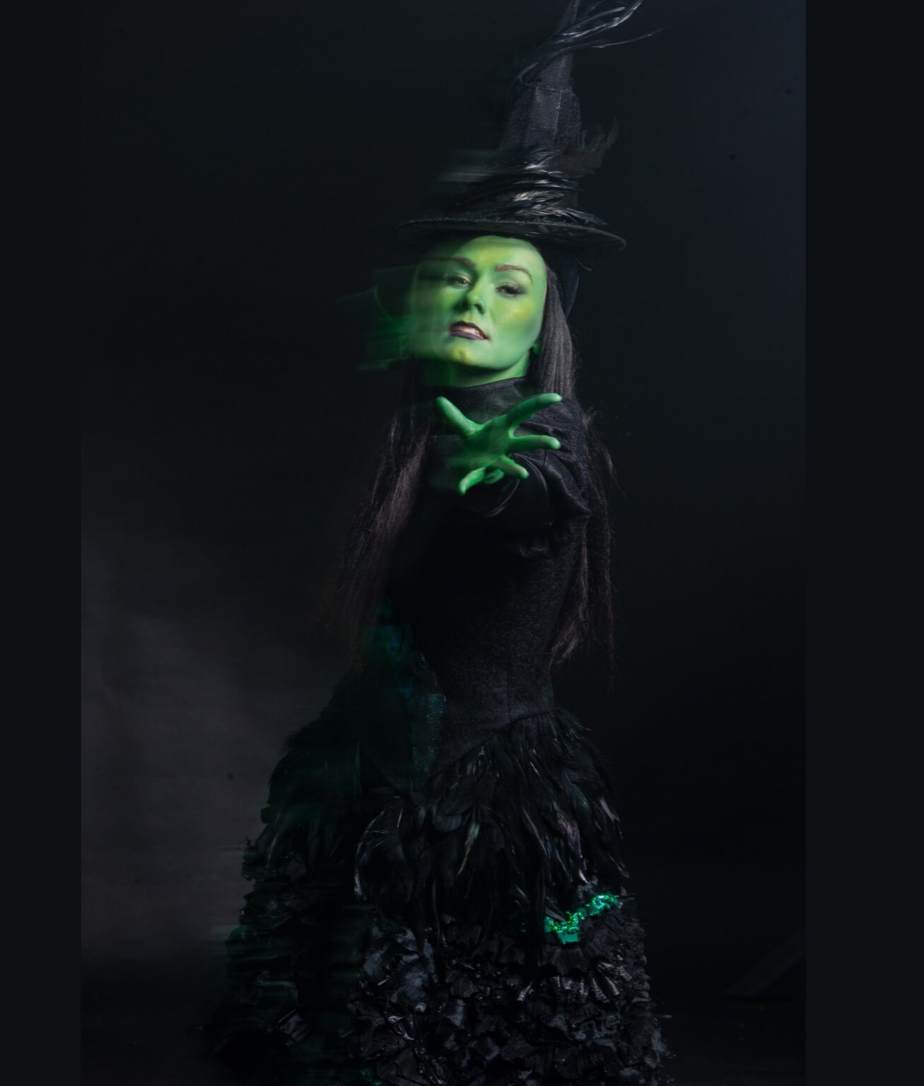 Kobieta pomalowana na zielono, ubrana w strój czarownicy
