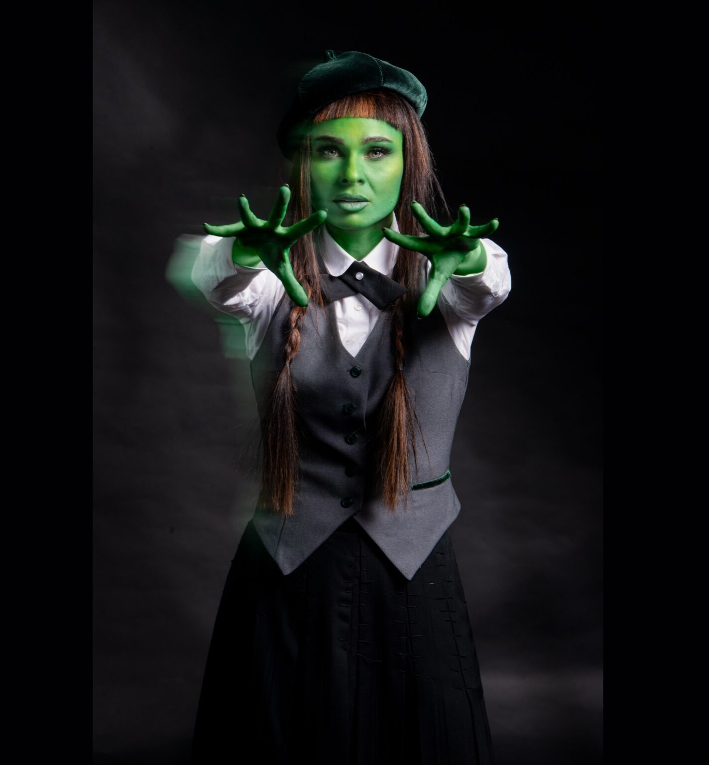 Kobieta pomalowana na zielono, ubrana w szary mundurek szkolny