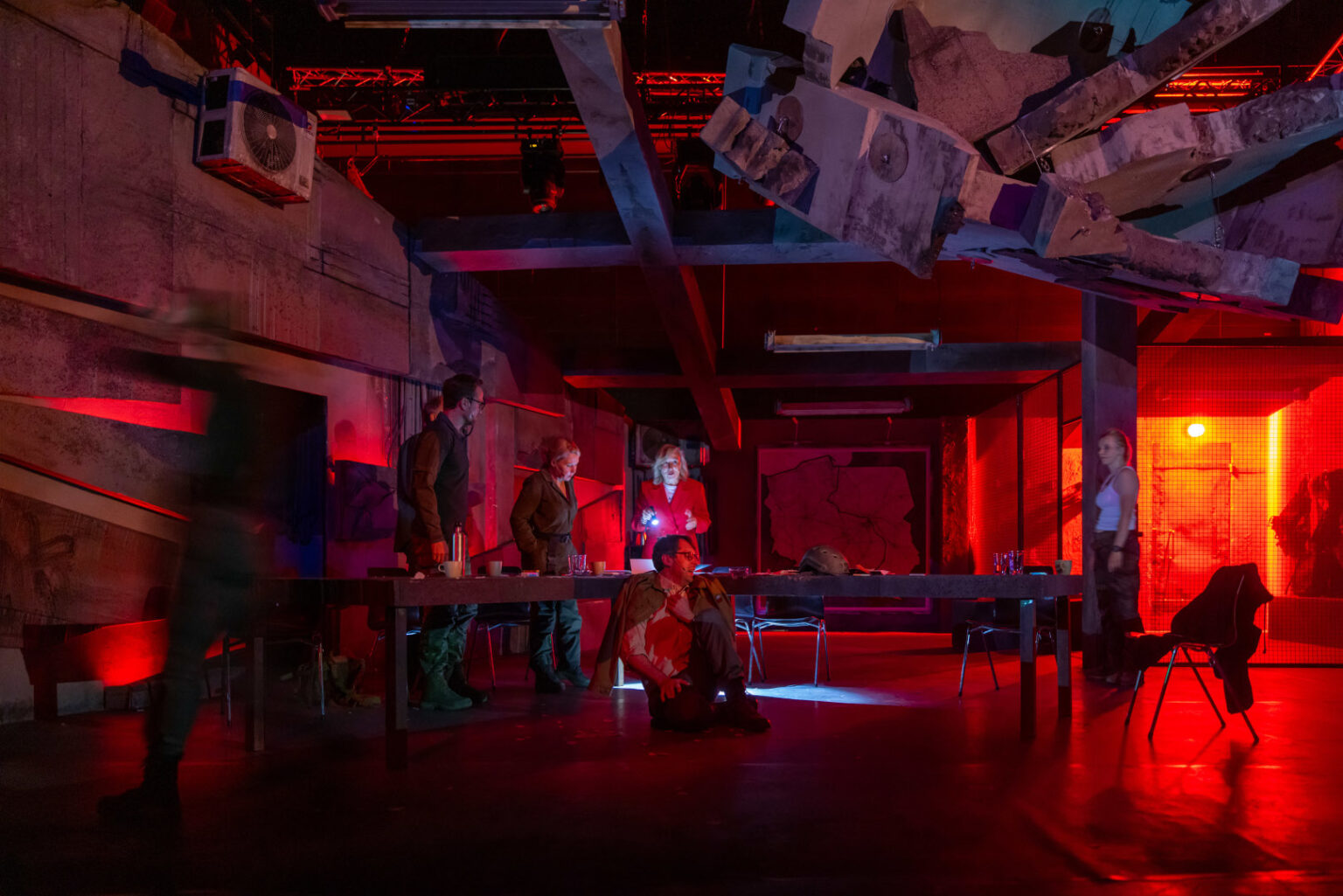 zdjęcie przedstawia grupę ludzi siedzących przy stole oświetlonego czerwonym światłem