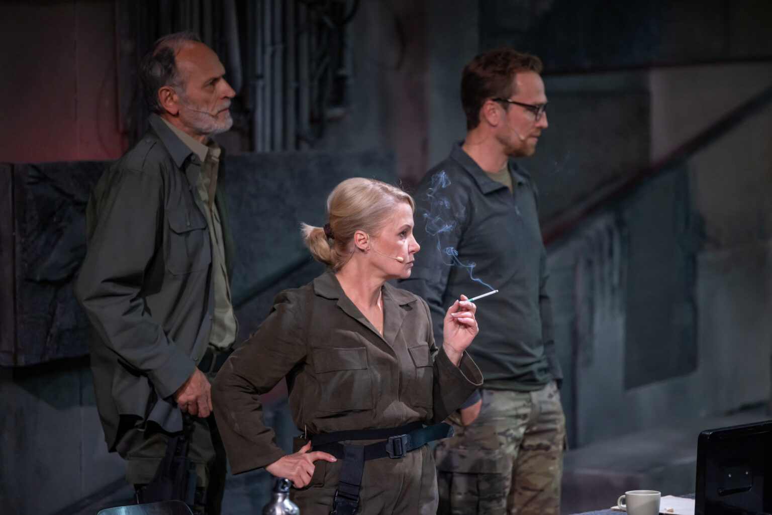 zdjęcie trójki ludzi. Kobieta trzyma w ręku papierosa