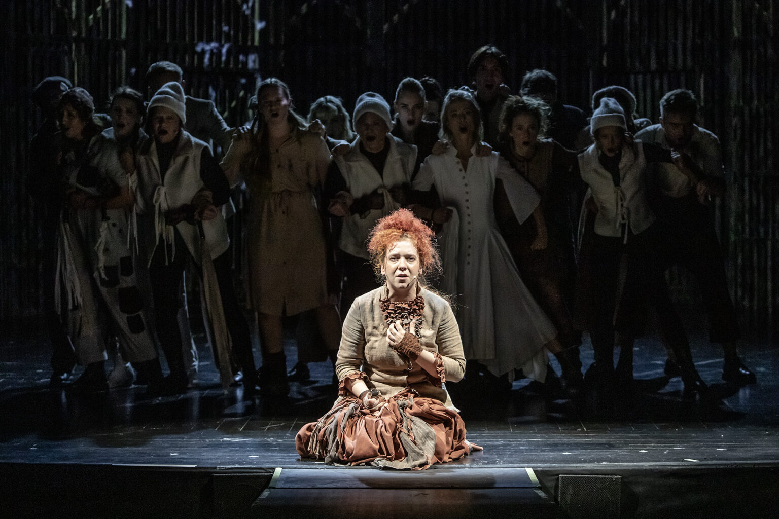 Zdjęcie ze spektaklu Folwark zwierzęcy, przedstawiający grupę ludzi ubranych w kostiumy inspirowane latami 60 w Polsce.