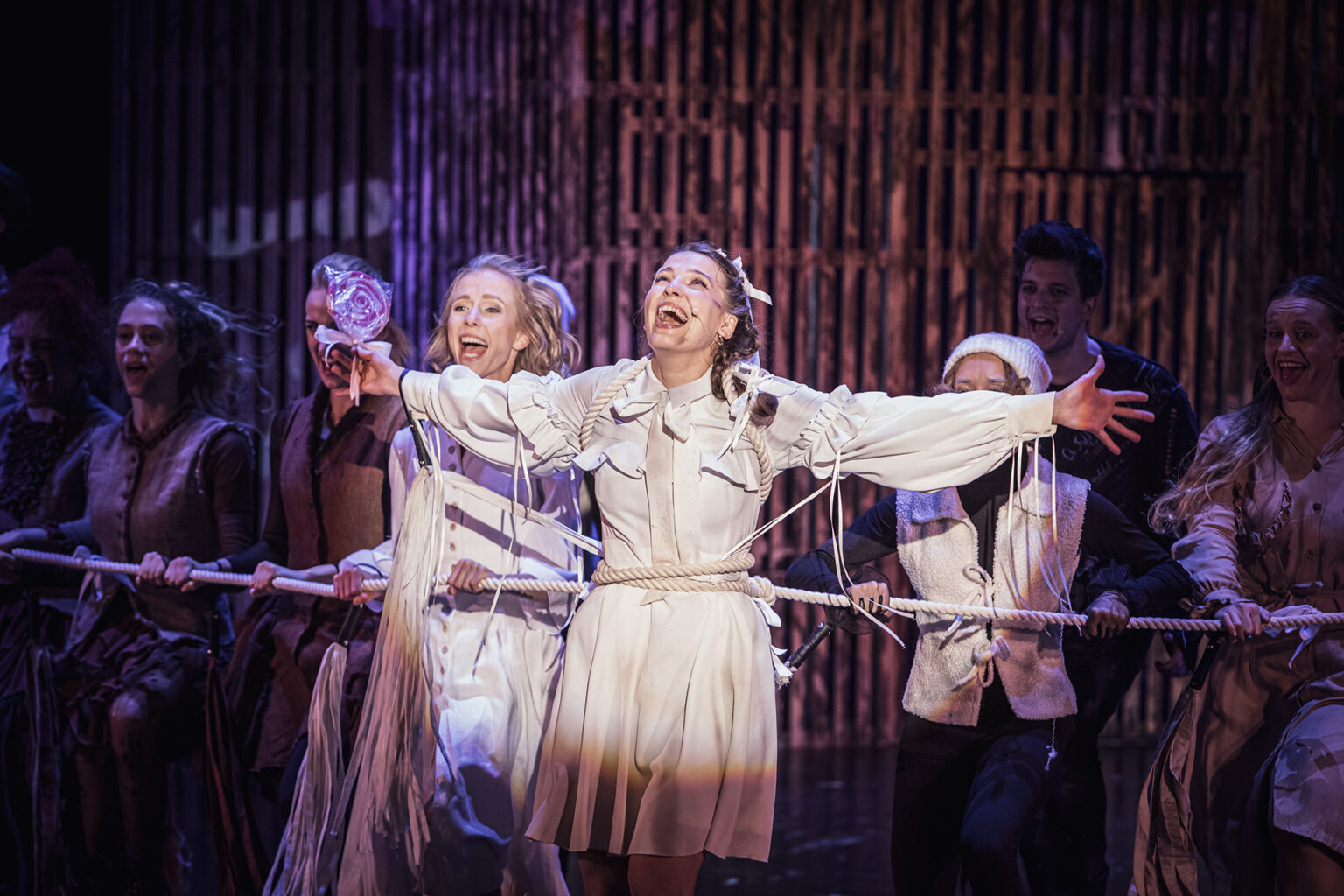 Zdjęcie ze spektaklu Folwark zwierzęcy, przedstawiający grupę ludzi ubranych w kostiumy inspirowane latami 60 w Polsce.