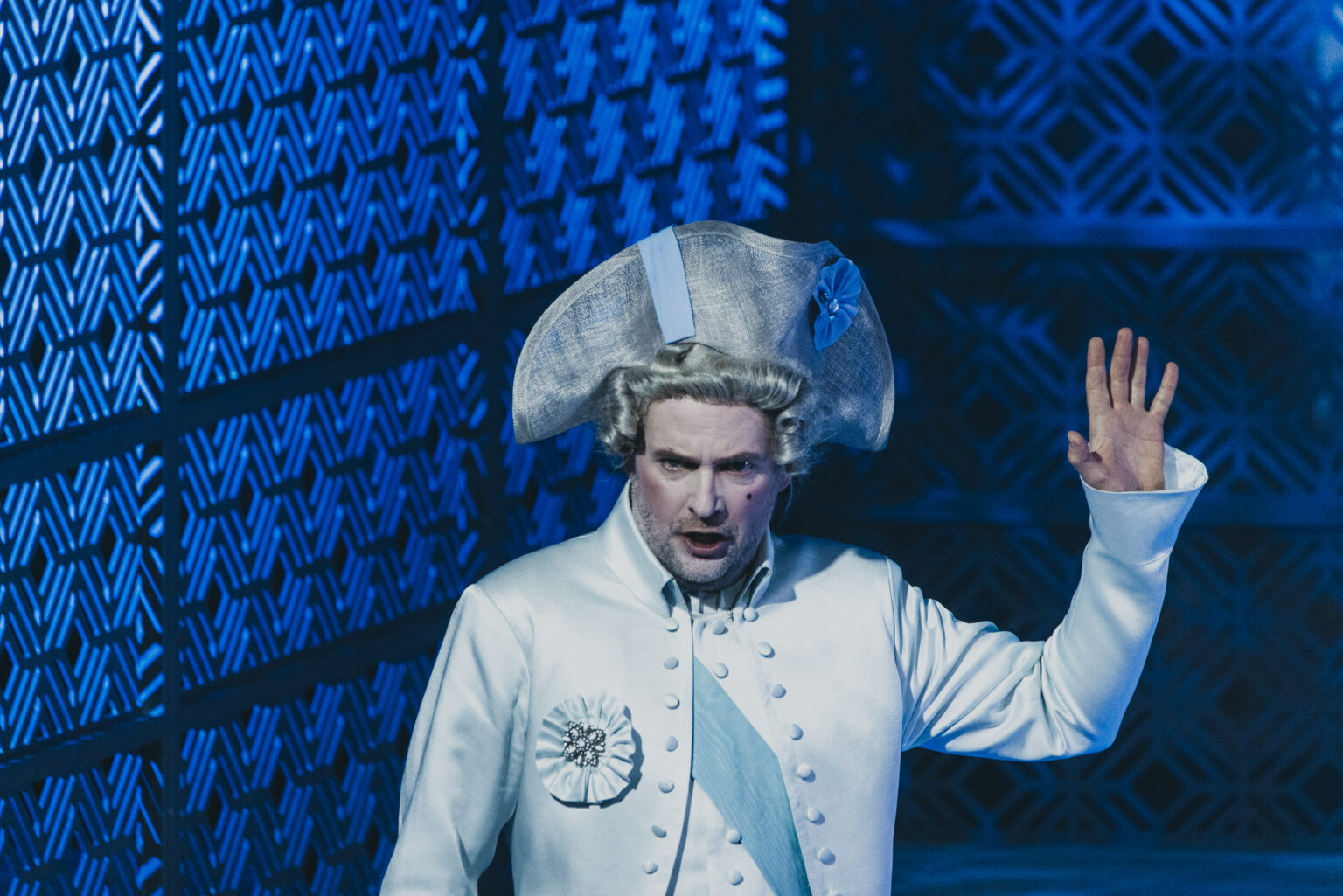 Mężczyzna. w jasnym, historycznym kostiumie, z nakryciem na głowie.