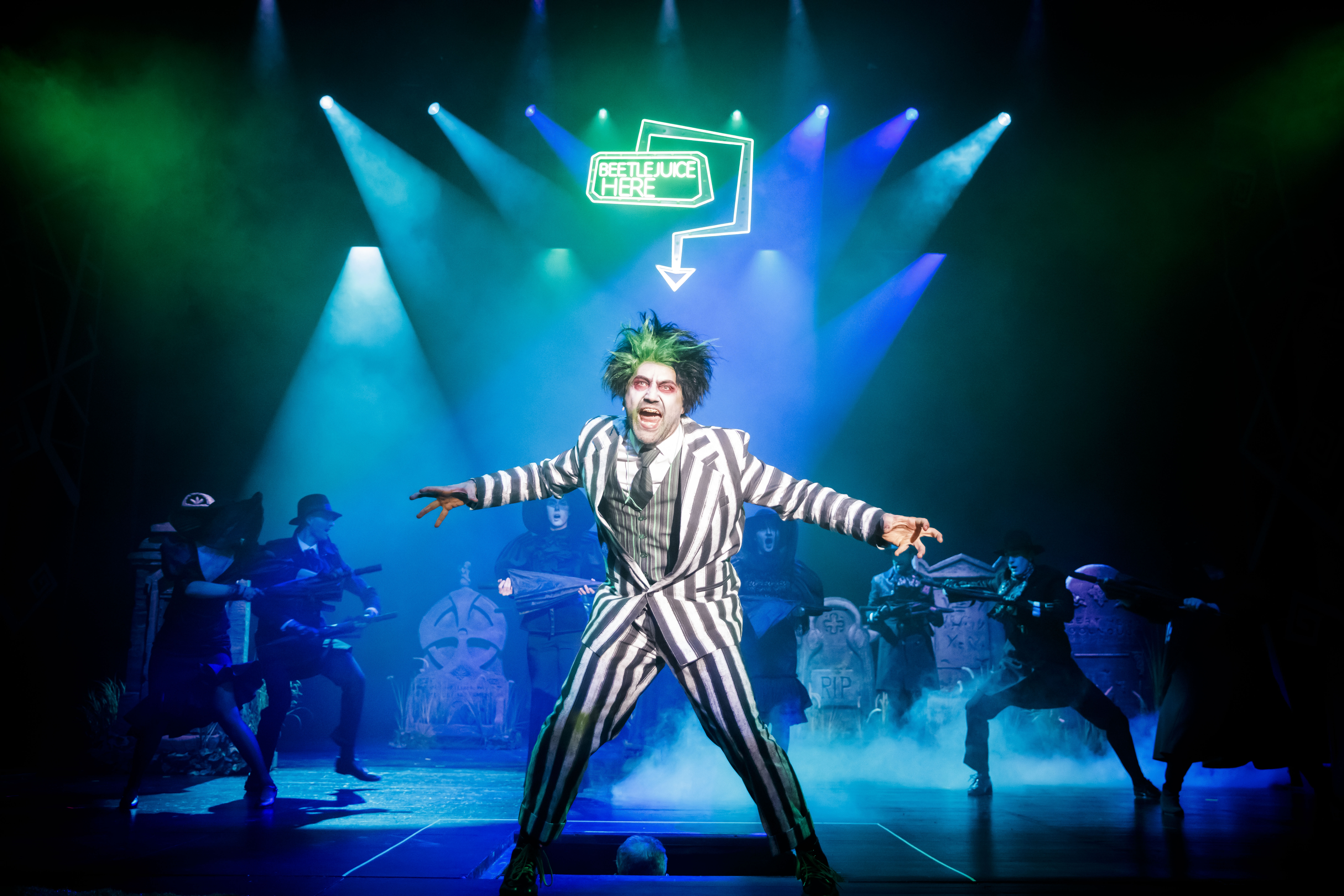 Zdjęcie grupowej sceny, na czele której stoi rozemocjonowany mężczyzna ubrany w garnitur w paski.