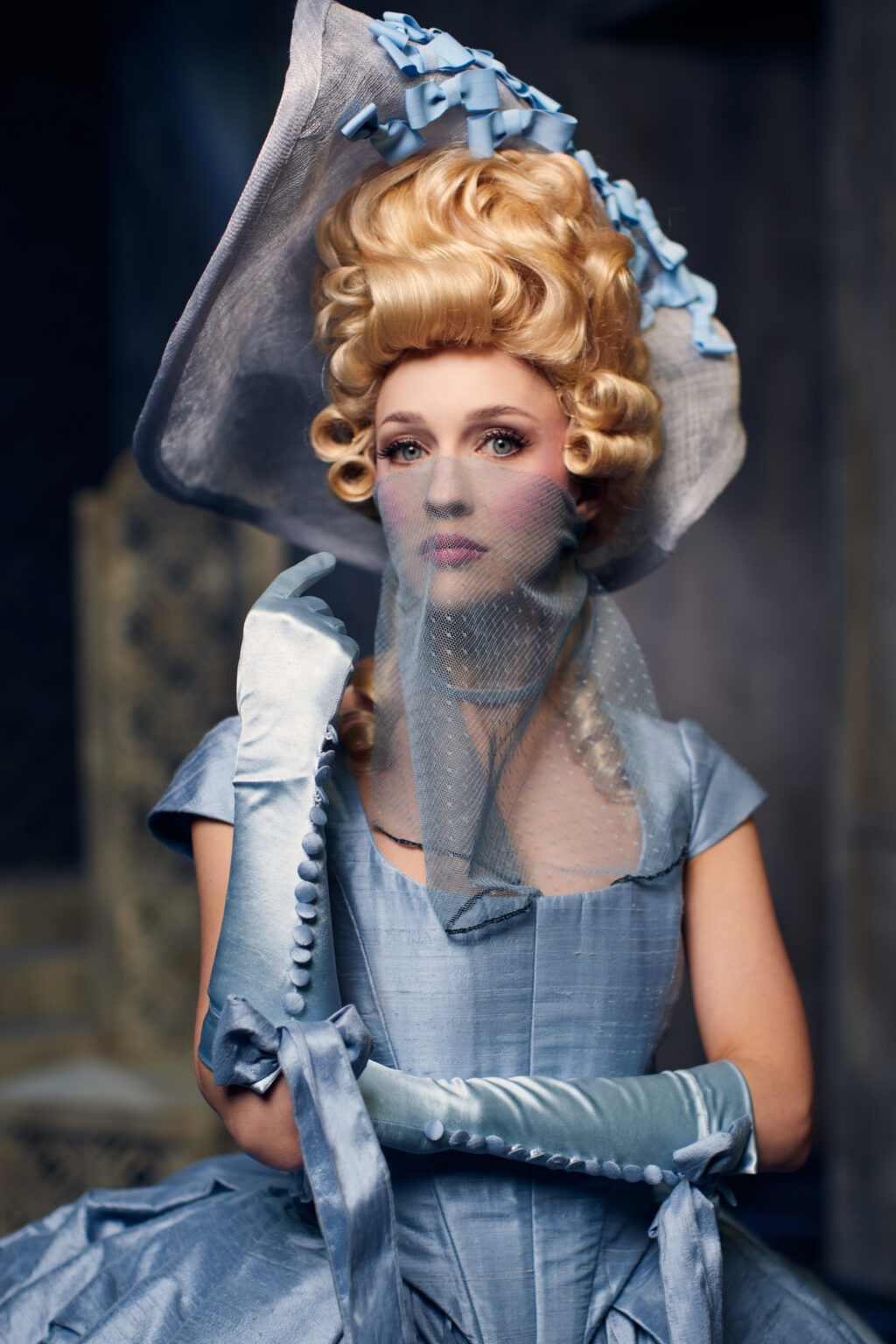 Zdjęcie młodej kobiety, ubranej w błękitny rokokowy kostium.