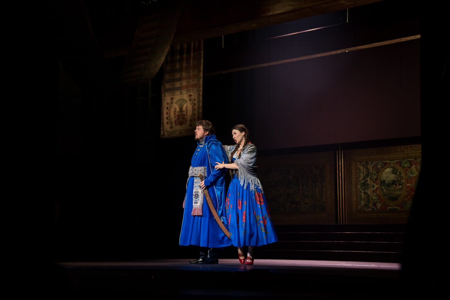 Zdjęcie przedstawia dwóch śpiewaków ubranych w piękne kostiumy w intensywnym, niebieskim odcieniu.