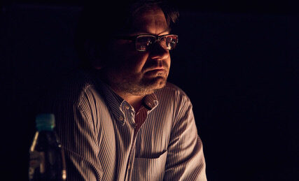 Mężczyzna oparty o stół w półmrooku