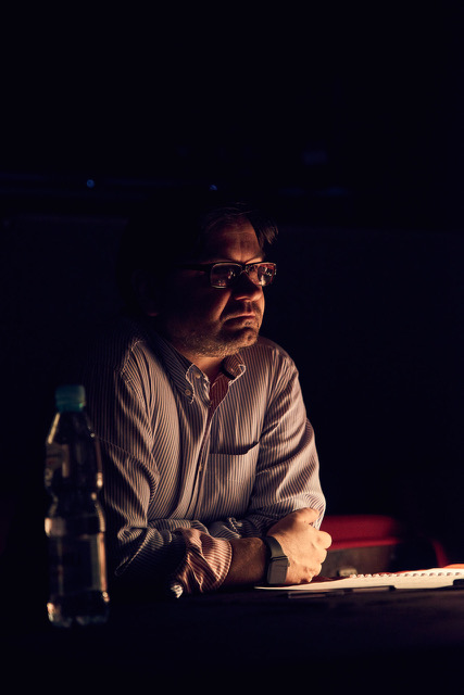 Mężczyzna oparty o stół w półmrooku